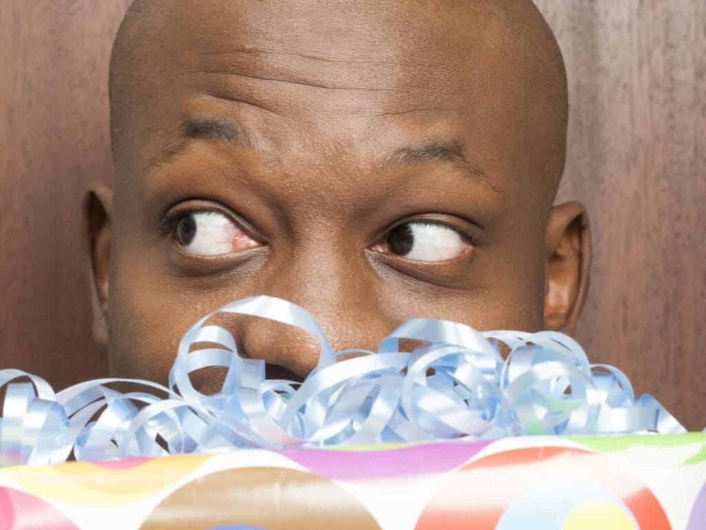 man holding birthday gift in front of his face