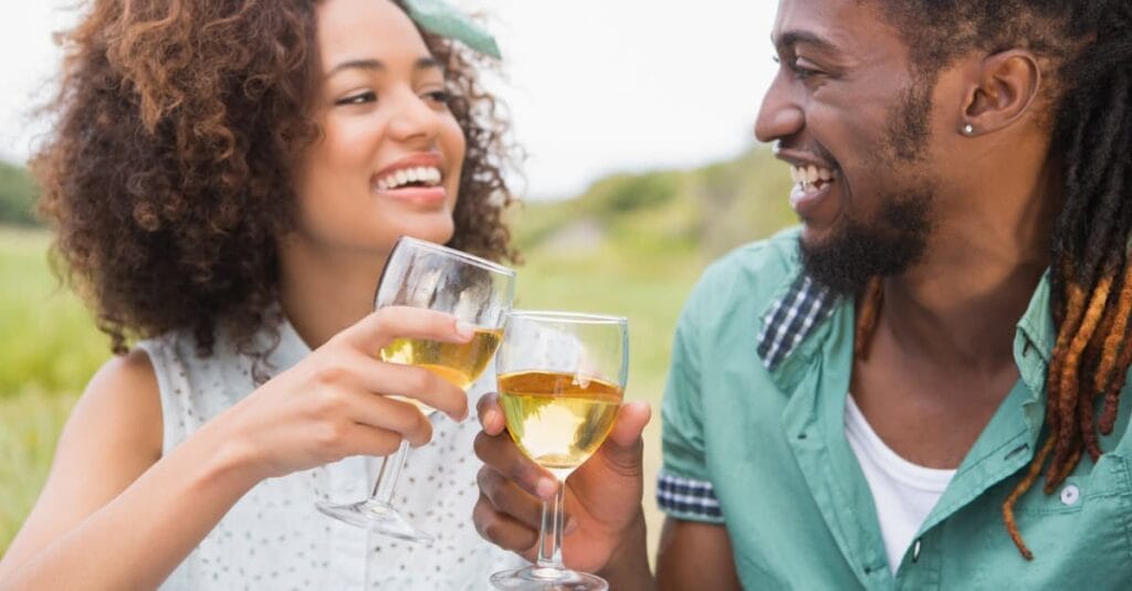 Young couple on a picnic drinking wine on a sunny day