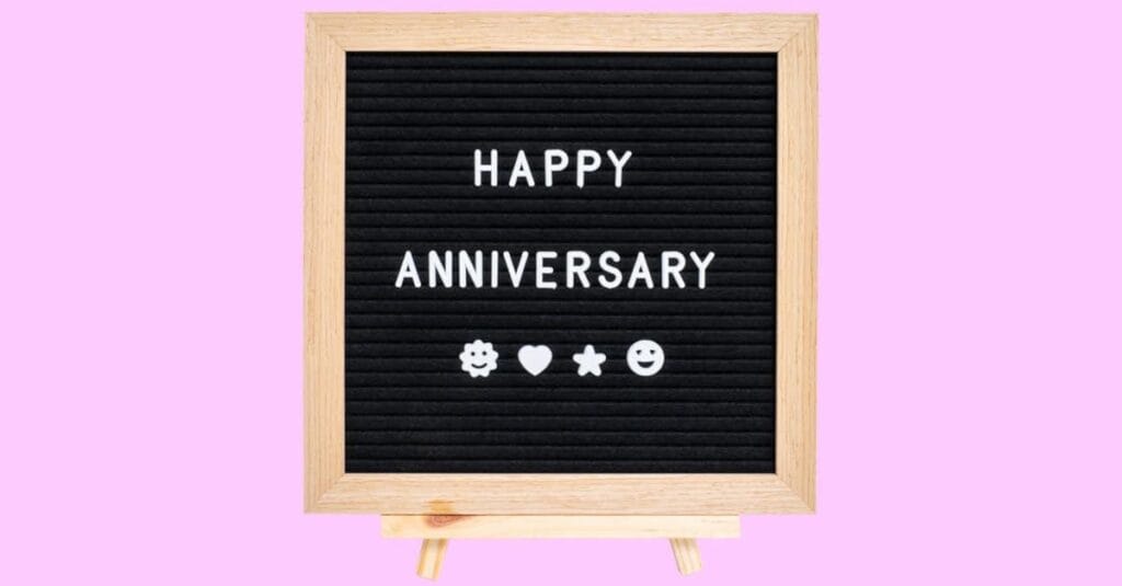 Closeup of board with happy anniversary word isolated on pink background